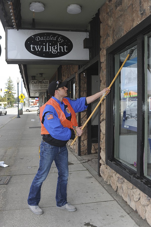 Forks Police Cadet Chas Schilling helped clean dirty windows downtown during the Spruce Up Forks community clean-up day.