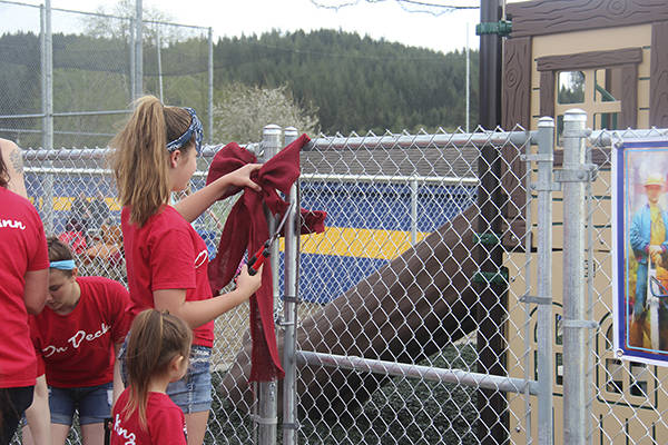 Kray Horton cuts the ribbon as Tod’s granddaughter Kinzie looks on, moments before they get their first opportunity to play on the playground equipment that bears his name. Photo Christi Baron