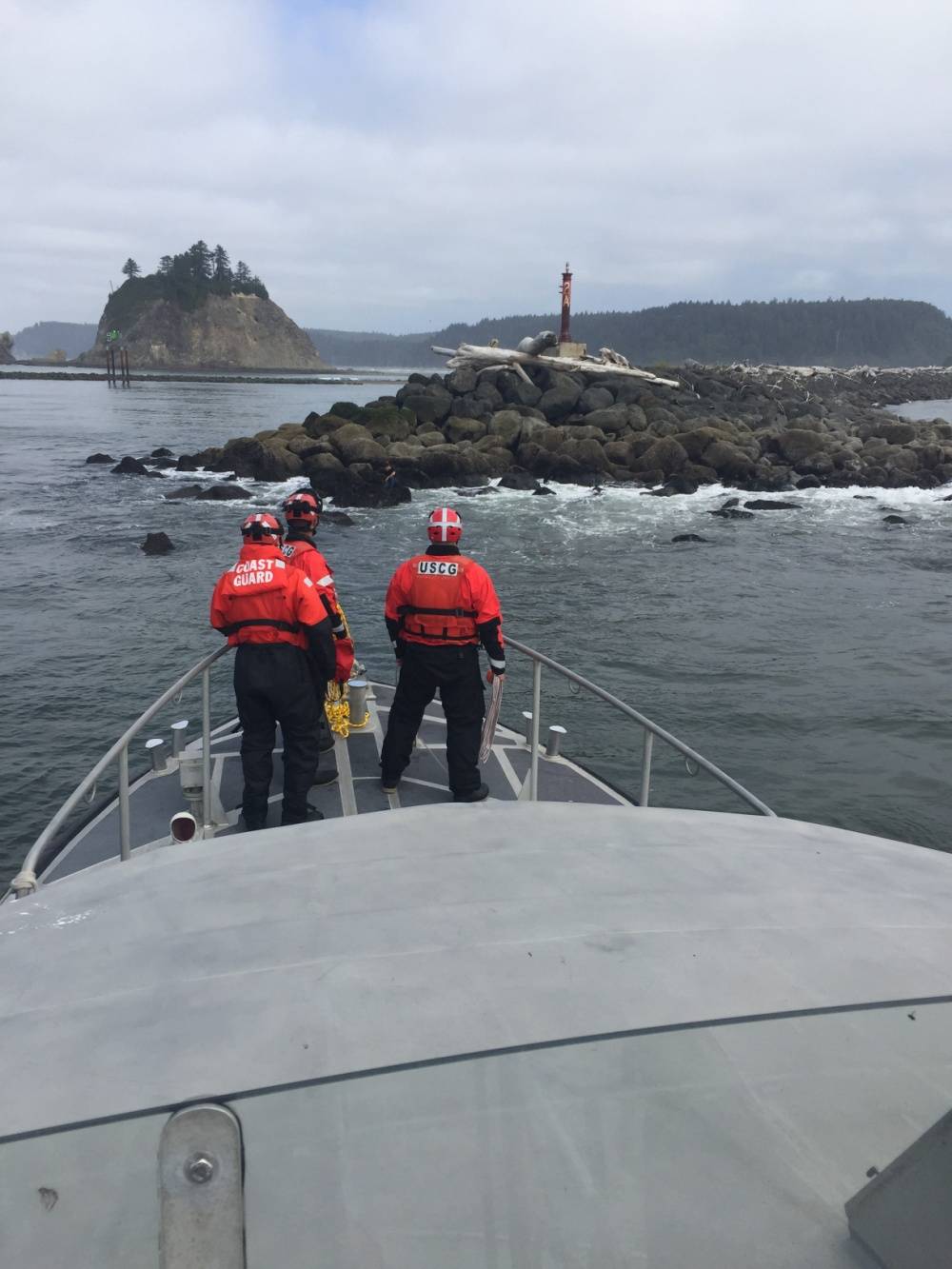 Coast Guard crewmembers aboard a 47-foot Motor Life Boat from Station Quillayute River located in La Push, Wash., prepare to rescue a swimmer sitting on rocks near James Island, Aug. 16, 2018.                                U.S Coast Guard photo by Petty Officer 1st Class Louis Keating.