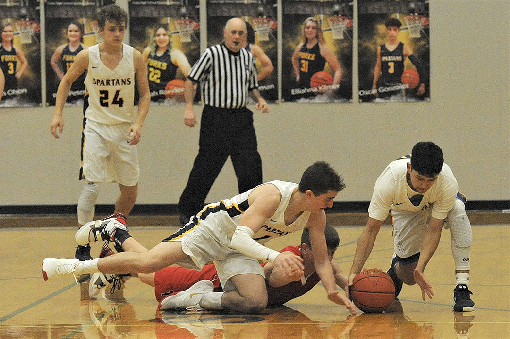 Above, Spartans Riley Pursley (21) and Tony Hernandez-Flores (right) hustle for a loose ball against Tenino in the Spartan Gym where Forks defeated the Beavers 63-48. Looking on is Logan Olson (24). Photo by Lonnie Archibald