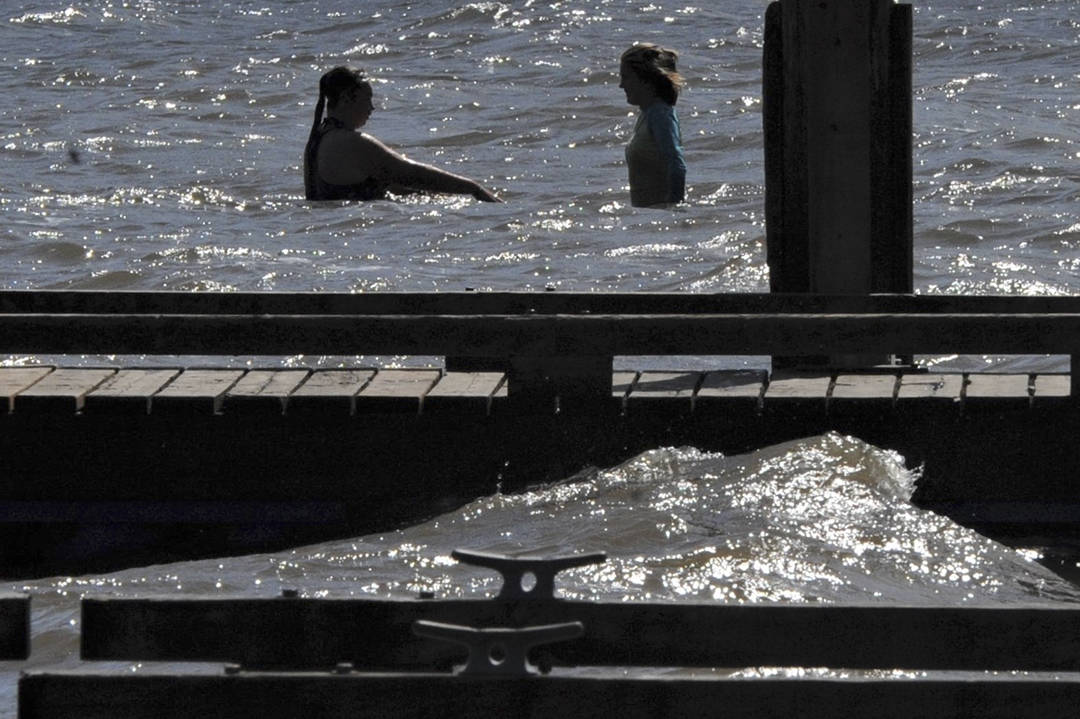 Swimmers are silhouetted against the morning sun while waves crash against the dock at the Lake Pleasant County Park. Strong northeasterly winds prevailed over the Labor Day Weekend. Photo by Lonnie Archibald