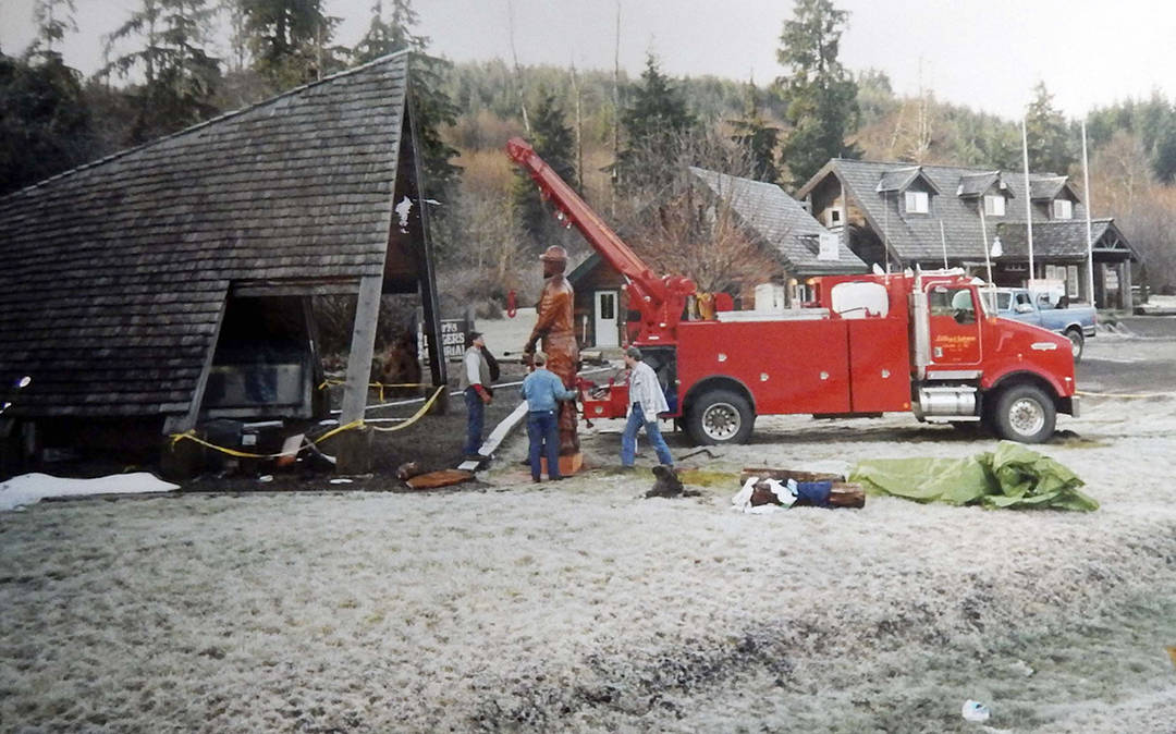 Volunteers Lynn Soloman, Kevin Fouts, and Darin Hoffman work to place the logger carving under the A-frame cover on a frosty day in 1992. Forks Forum Archives