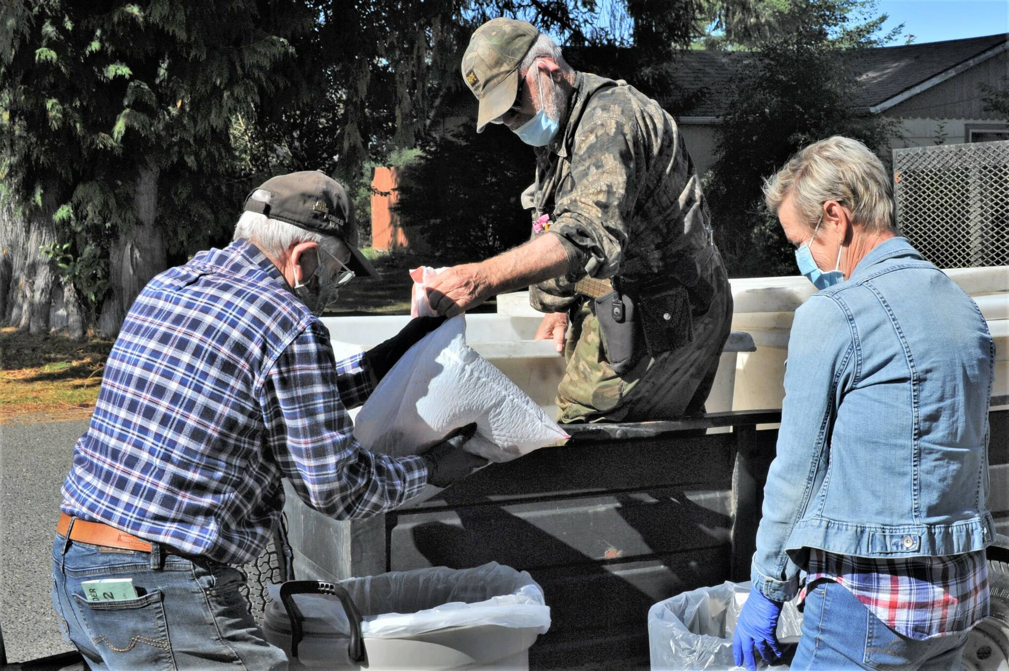 Wayne Haag (center) hands fish fillets to Glenn King and Terri Rasmussen of the Forks Food Bank.  The masons also received fish for distribution, as did several individual families.  That day, 160 Coho were treated by PCSC volunteers.