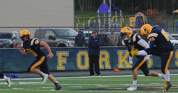 Forks head coach Trevor Highfield looks on while Spartan kicker Hector Dominguez kicks the ball into the endzone.  Also in the action are Nate Dahlgren (40) and Landon Davis (5).  Photo by Lonnie Archibald