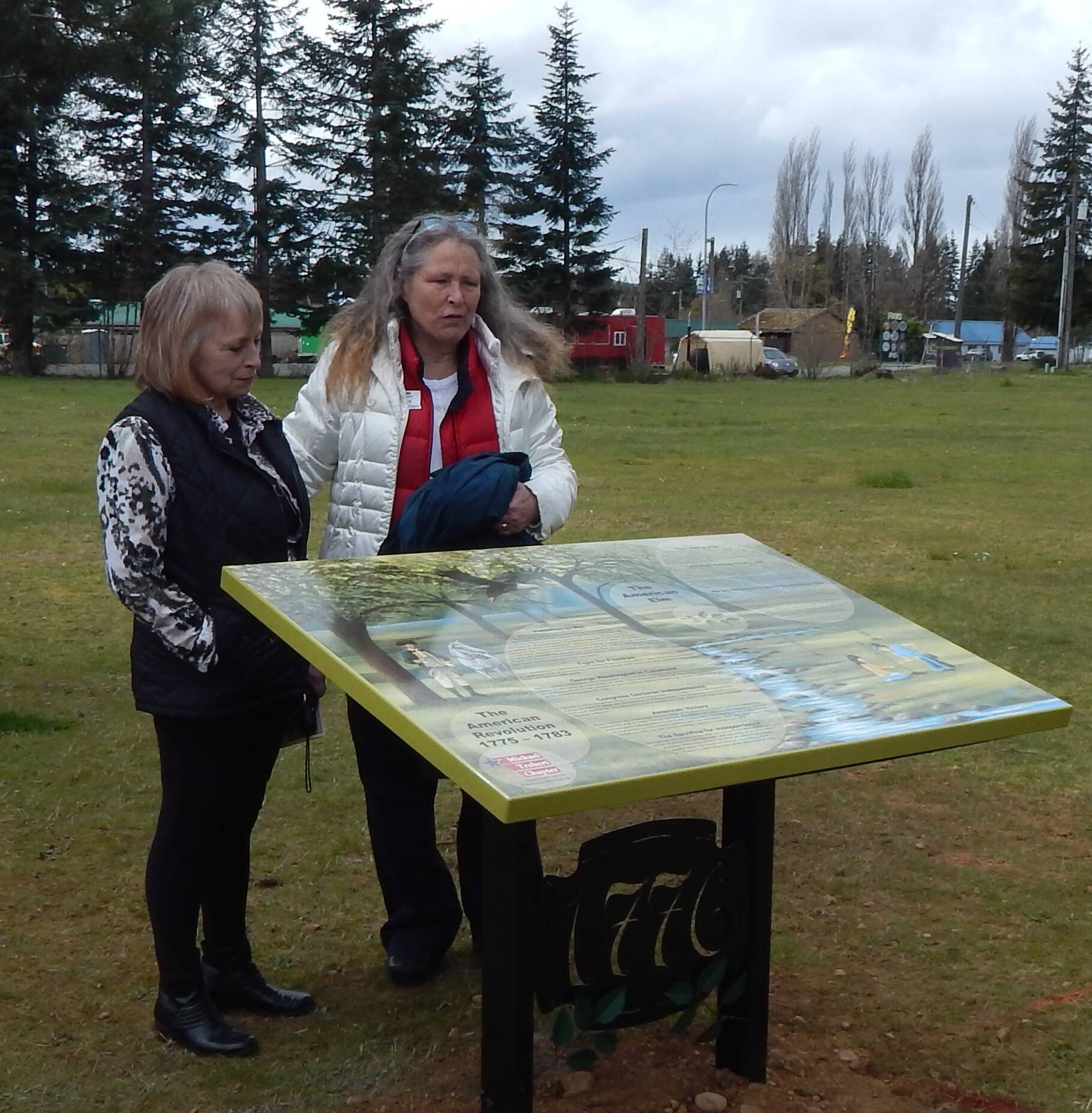 Signage describing the American Elm Project is located at Tillicum Park just before the play equipment. The artwork was done by local artist Carol Simons and the stand the sign sits on was created by Hickory’s Welding Service of Forks; complete with metal elm leaf sprigs at the base. After the unveiling on Friday Carol is seen here with Cynthia Bork who spearheaded the Elm project in Forks.