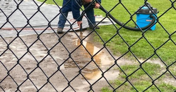 When mother nature gives you rain … get out the Shop-Vac! Danny Winger is seen here Saturday morning vacuuming the field. Later Winger was seen wearing a life jacket. Photo Christina Jennings