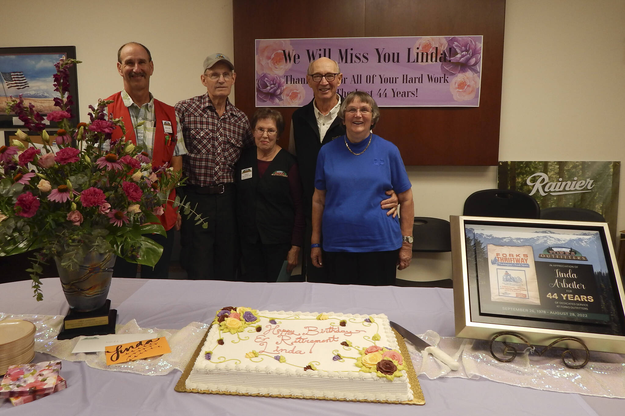 Bruce Paul, Phil Arbeiter, Linda, and former Outfitter’s owners Bert and Martha Paul stand behind the flowers, cake and beautiful plaque that were bestowed on Linda last Friday. It was also her birthday!