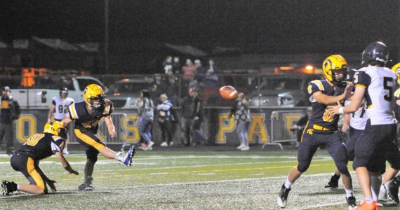 Landen Olson (10) holds while kicker Walker Wheeler (23) kicks another ball through the uprights. Blocking is Camryn Kennedy (8). Photo by Lonnie Archibald
