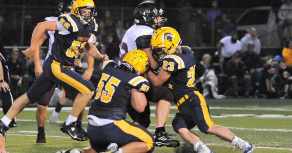 Spartans Brady Lausche (56), Sloan Tumaua (55), and Walker Wheeler (23) bring down the Raven running back. Photo by Lonnie Archibald