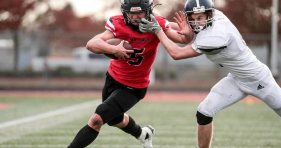 Neah Bay quarterback Julian Carrick is facemasked by a Liberty Christian defender on one of his big runs Saturday in the state 1B semifinals held at Mount Tahoma High School in Tacoma. Carrick scored six touchdowns as Neah Bay won 82-24. The Red Devils will face Liberty Bell next week in the championship game. (Maria Dorsten/for Peninsula Daily News)i
