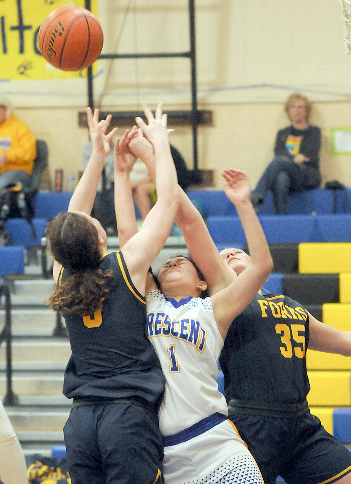 Crescent’s Ciara Cargo-Acosta, center, reaches for a rebound and is squeezed by Forks’ Keira Johnson, left, and Kyra Neel during Wednesday’s game at Crescent High School. (Keith Thorpe/Peninsula Daily News)
