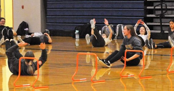 Seen here is just a portion of the 52 athletes turning out for track and field as they warm up in the Spartan gym where temperatures were much warmer than those out on the track. Photo by Lonnie Archibald