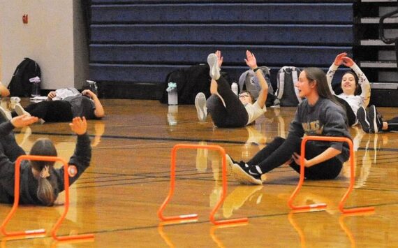 Seen here is just a portion of the 52 athletes turning out for track and field as they warm up in the Spartan gym where temperatures were much warmer than those out on the track. Photo by Lonnie Archibald