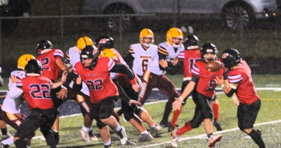 Red Devil quarterback Josh Greene pitches to running back JoJo Wimberly who ran in another touchdown against the Cardinals during a rainy and windy game last Friday. Photo by Lonnie Archibald