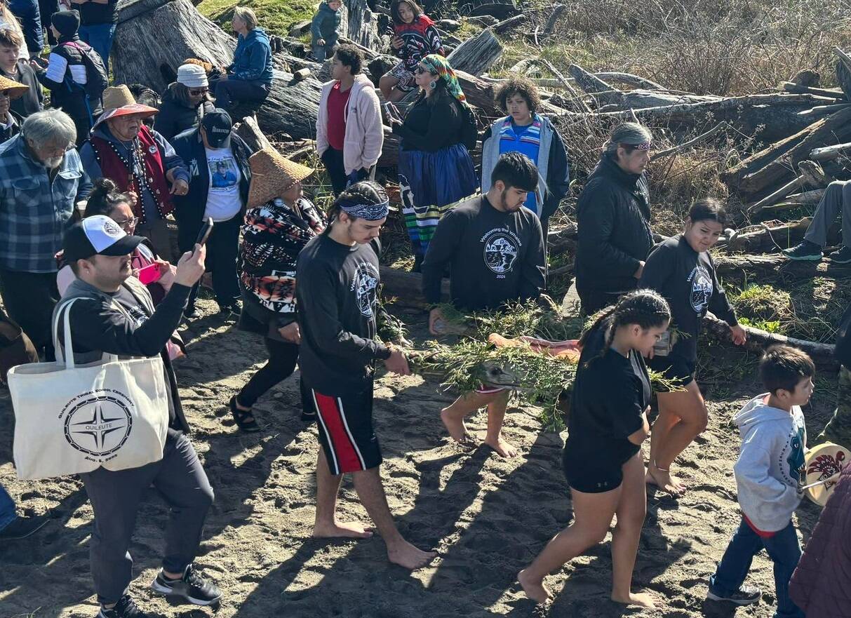 The crowd follows as students make their way to the beach to send off the offering of salmon.