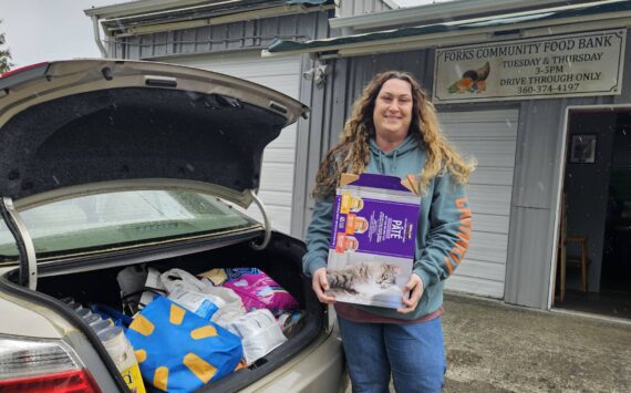 Sena Engeseth, Forks Food Bank, recently accepted donated pet food from Friends of Forks Animals. The pet food was donated by generous community members from the Forks area to Friends of Forks Animals. Submitted photo