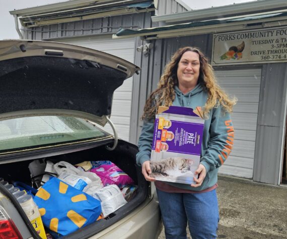 <p>Sena Engeseth, Forks Food Bank, recently accepted donated pet food from Friends of Forks Animals. The pet food was donated by generous community members from the Forks area to Friends of Forks Animals. Submitted photo</p>