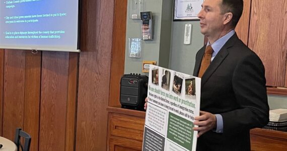 Nichols holds a sample of the posters that will be placed around county properties, advising potential trafficking victims of what they can do. Photo Christi Baron