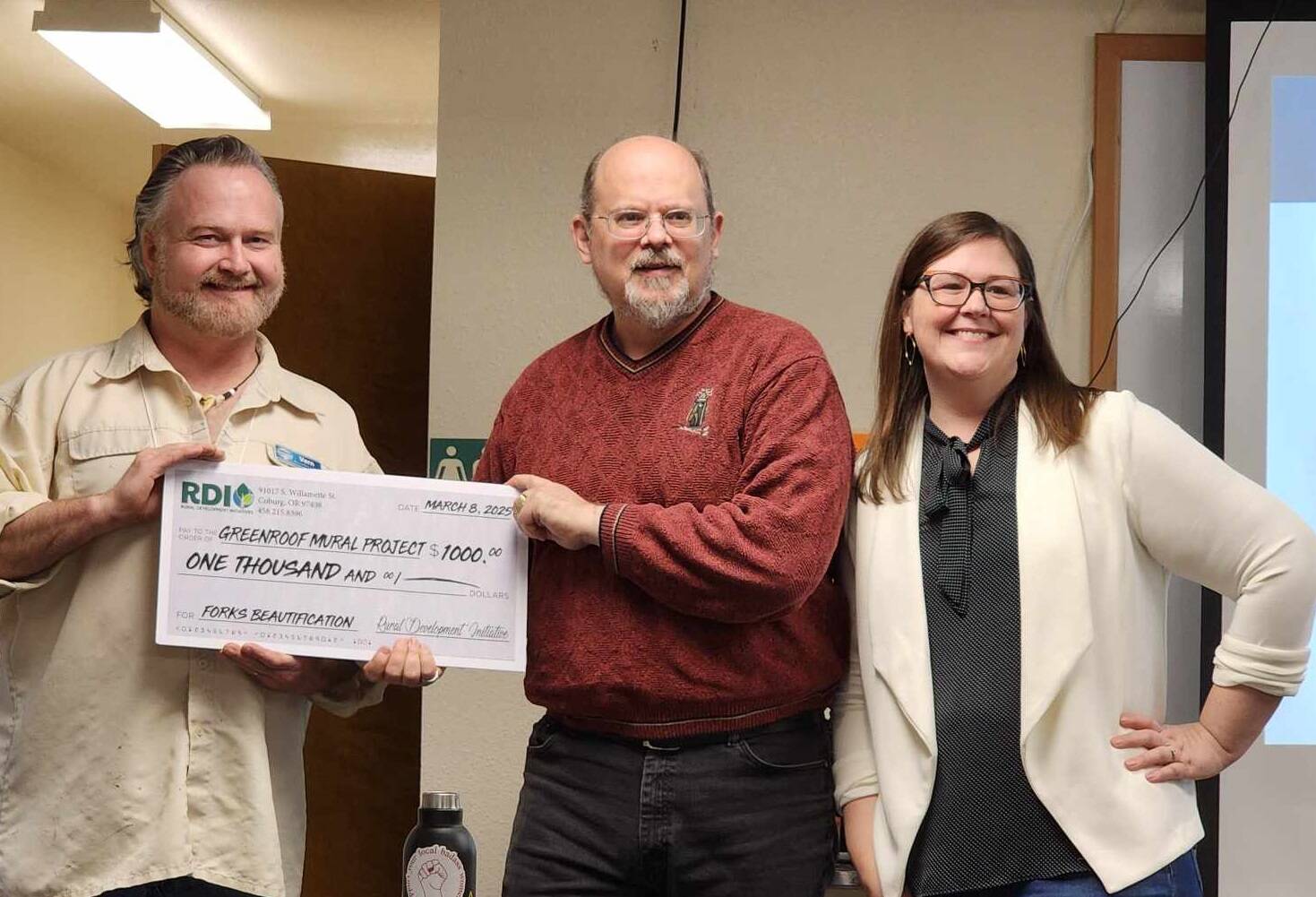Vern Hestand accepts a $1,000 grant for his mural project. Also in the photo is Rod Fleck with the city of Forks and Gilmore.