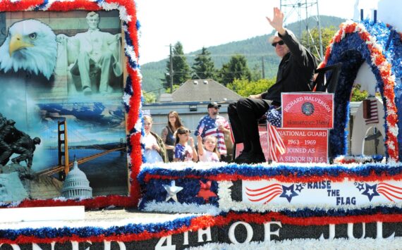 Photo Lonnie Archibald
Hometown Hero Richard Halverson waves to the Grand Parade crowd on the 4th. Halverson joined the National Guard while he was still in high school and served from 1963-1969. Richard has volunteered for the Forks Chamber’s Logging and Mill tour and served on the boards of the Forks Timber Museum and the West End Historical Society.