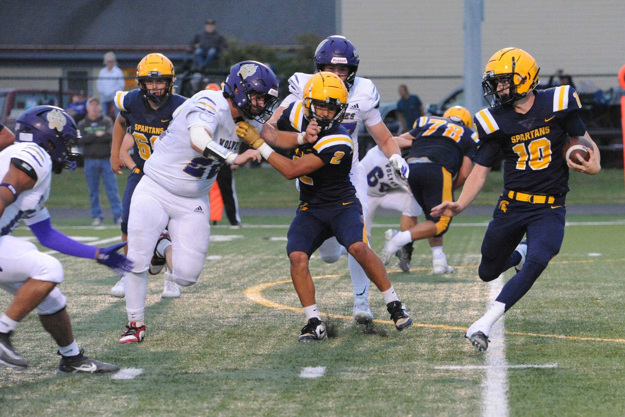 Spartan Quarterback Landen Olson runs behind the blocking of Noah Foster (2) on the turf of Spartan Stadium Friday Sept. 5 where the 2A Sequim Wolves held on to defeat Forks 18 to 14.