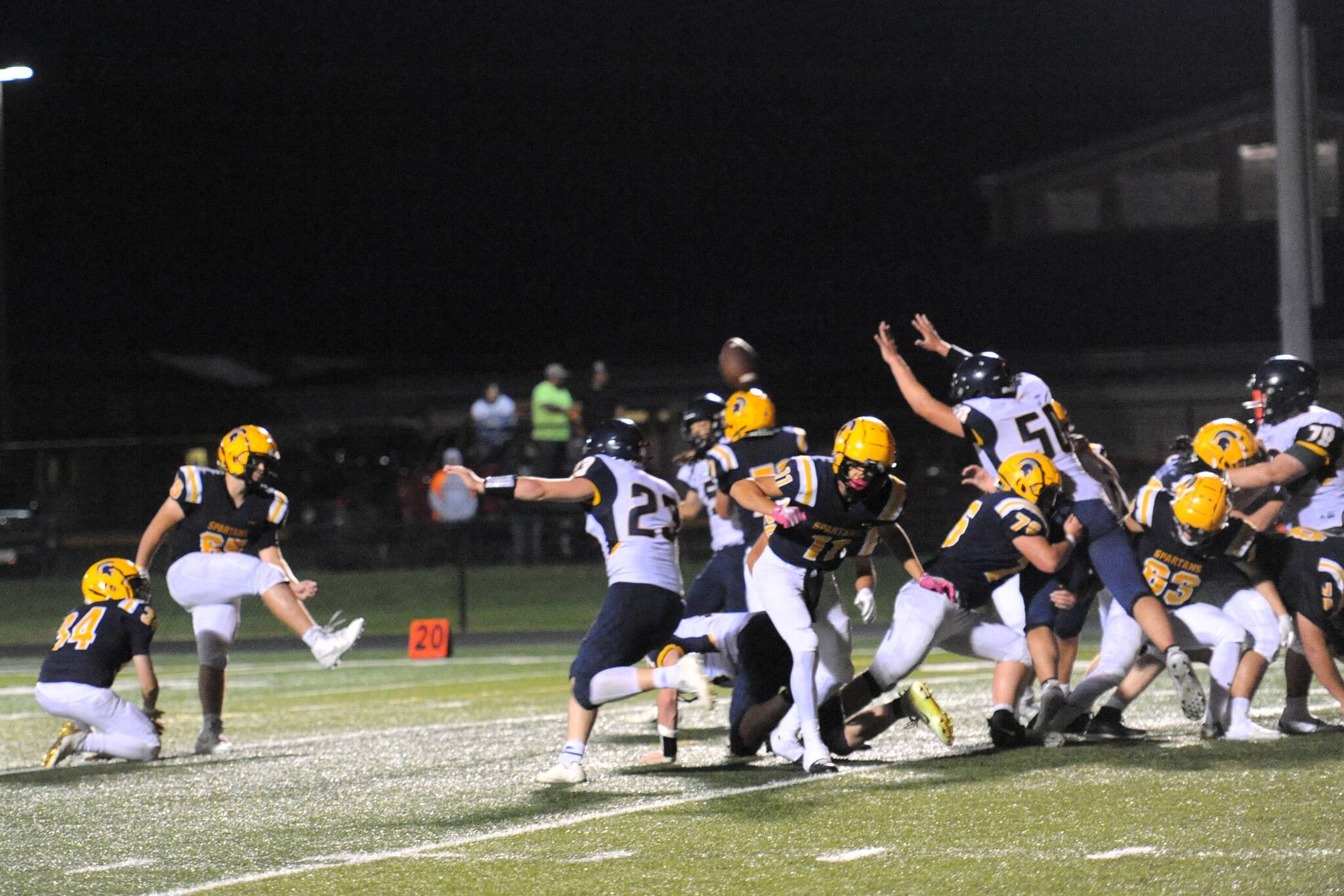Photo by Lonnie Archibald
Spartan Tannon Gaydeski holds for kicker Mario Reyes (65) as another of Reyes’ kicks splits the uprights. Reyes was 4 for 4 on extra points and also nailed a 35-yard field goal to begin the game. It takes a stout offensive line, a good snap, a good hold, and a good kick, and the Spartans had it all Friday night as they defeated the Fishermen 37 to 33 before a large homecoming crowd.