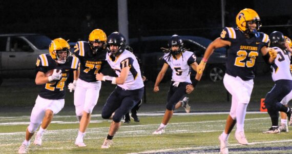 Spartan Kingston Steffen (24) runs behind the blocking of Kaden Ward (23) and Carter Coberly (77).