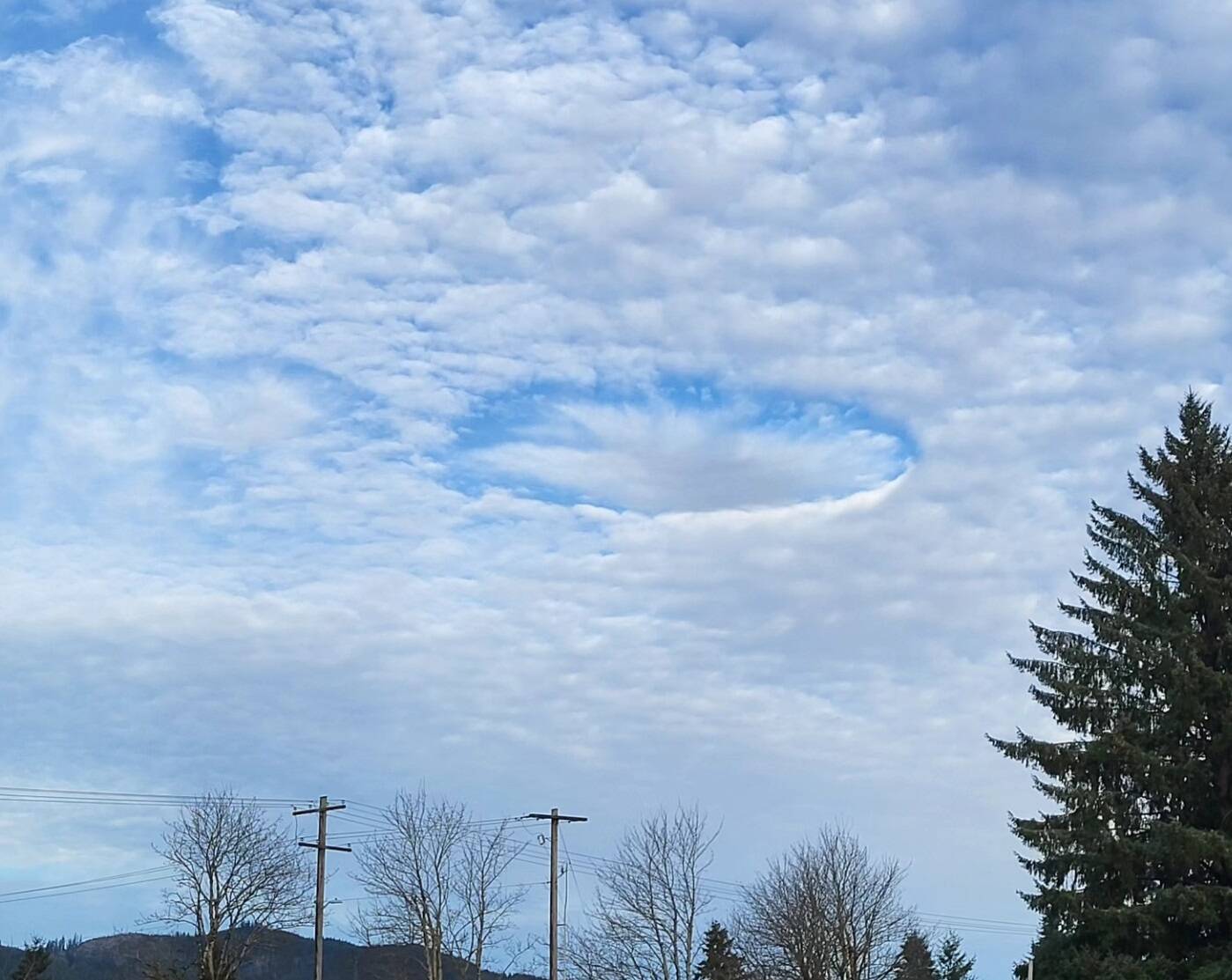 Last Wednesday, many looked up to say …its a bird, its a plane its …not Superman …so what was it?
A fallstreak hole (also known as a hole punch cloud) is a large circular or elliptical gap that can appear in cirrocumulus or altocumulus clouds. High to mid-level clouds, such as altocumulus, are often composed of tiny water droplets that are much colder than freezing, but have yet to freeze. These supercooled water droplets need a reason to freeze, which usually comes in the form of ice crystals. Planes passing through the cloud layer can bring these ice crystals.
Once the ice crystals are introduced, the water droplet quickly freeze, grow and start to fall. A hole is left behind, which will start to expand outward as neighboring droplets start to freeze. Photo Rod Fleck