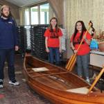 QVSA organizer David Hurn and student Scholarship Auction coordinators, Madelyn Archibald and Olivia Gonzalez gather around a custom-built wooden canoe donated by Rich McMenamin Saturday during the auction. Photo by Lonnie Archibald