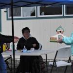 Auction pick-up. QVSA board member Edith Henry turned over a cottage birdhouse donated by OCC to Sara Palmer Sveum while QVSA member Cheri Dahlgren looks on. Bidders picked up their items outside the Forks Congregational Church while students took bids and handled items inside. Photo by Lonnie Archibald