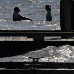 Swimmers are silhouetted against the morning sun while waves crash against the dock at the Lake Pleasant County Park. Strong northeasterly winds prevailed over the Labor Day Weekend. Photo by Lonnie Archibald