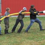 Pastor/chaplain Andy Pursley helps a group of grade school students handle the hose Friday, Sept 18 at the Beaver Fire Hall where these youngsters besides taking a ride on the fire truck learned the ways of fire fighting. Local fire departments are always searching for volunteer firemen. Perhaps Fire District #1 Beaver has found some future recruits. Photos by Lonnie Archibald