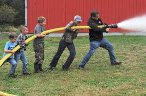 Pastor/chaplain Andy Pursley helps a group of grade school students handle the hose Friday, Sept 18 at the Beaver Fire Hall where these youngsters besides taking a ride on the fire truck learned the ways of fire fighting. Local fire departments are always searching for volunteer firemen. Perhaps Fire District #1 Beaver has found some future recruits. Photos by Lonnie Archibald