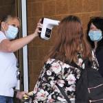 Connie Munson (left) and Tina Hagen take temperatures and hand out masks to students as they enter FHS Monday, Oct. 5 for the first day of school.
