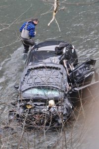 A fisherman examines the wrecked vehicle in the cold waters of the Hoh River. Photos by Lonnie Archibald