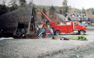 Volunteers Lynn Soloman, Kevin Fouts, and Darin Hoffman work to place the logger carving under the A-frame cover on a frosty day in 1992. Forks Forum Archives