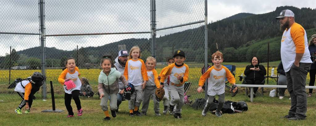 The Pirates rush onto the field to take their positions. Well, some took their positions only with help from the coaches. At times they might end up with two or three shortstops with no second or third baseman but those in charge soon got that situation straightened out.These future Spartans soon had it figured out, however, and all was well. Well sort of anyway. Oh yes, and the catcher, far left, was carrying too heavy of a load to be running with the team so he took time out to adjust his chest protector. Photo by Lonnie Archibald