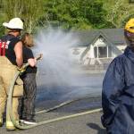 Deputy Chief Adam Campbell instructs Nancy Spieker, in using the fire hose.
