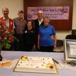 Bruce Paul, Phil Arbeiter, Linda, and former Outfitters owners Bert and Martha Paul stand behind the flowers, cake and beautiful plaque that were bestowed on Linda last Friday. It was also her birthday!