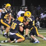 Spartans Brady Lausche (56), Sloan Tumaua (55), and Walker Wheeler (23) bring down the Raven running back. Photo by Lonnie Archibald