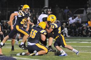 Spartans Brady Lausche (56), Sloan Tumaua (55), and Walker Wheeler (23) bring down the Raven running back. Photo by Lonnie Archibald
