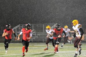 Red Devil QB Julian Carrick (5) finds running room behind the blocking of teammates Jodell Wimberly (1) and Charles Halttunen (12) during a rainy evening in Forks where Neah Bay defeated Winlock 56 to 6 earning their way into the state playoffs in 1B 8 man football. The Red Devils will face the winner of the Pomeroy/ Wellpinit game on Nov 18 or 19 with the time and place yet to be determined. Photo by Lonnie Archibald