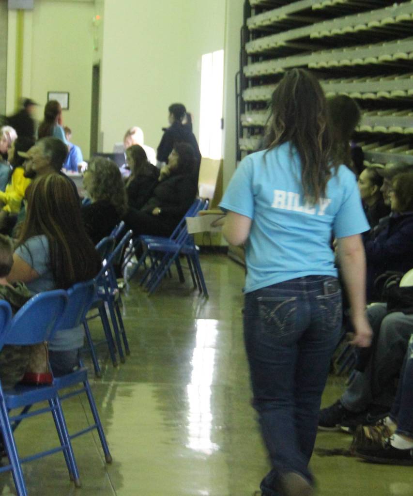 Riley Smith walks an item around the room at the Forks High School Commons so that potential bidders could get a better look. Photo Christi Baron