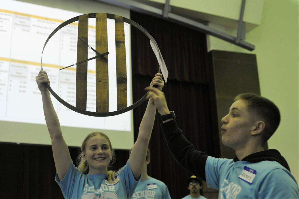 Kadie Wood holds up a whiskey barrel clock while Klayton Helvey comments on the item up for bid. Photo by Lonnie Archibald