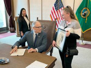 Dawn Reid, right, shows Gov. Jay Inslee a pencil drawing of her daughter, Kimberly, after Inslee signed a bill titled with Kimberlys name. State Rep. Debra Lekanoff, left, took part in the ceremony. (Gabe Galanda)