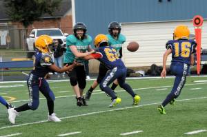 Forks 8th-grade quarterback Thomas Penn pitches to running back Ryder Fletcher (16) while Andres Silva (62) blocks during a game played at Spartan Stadium where Sequim defeated the Spartans 25 to 12. Photo by Lonnie Archibald