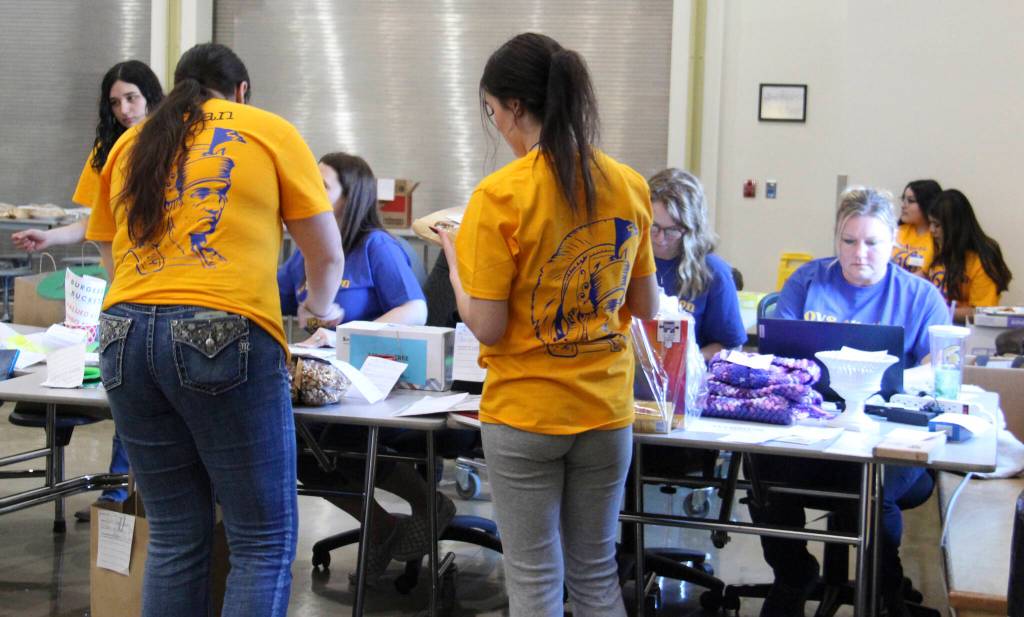 In their gold shirts, seniors helped bring sold items over to senior moms - Laci, Jessi and Shannon. They then logged in items that were sold.