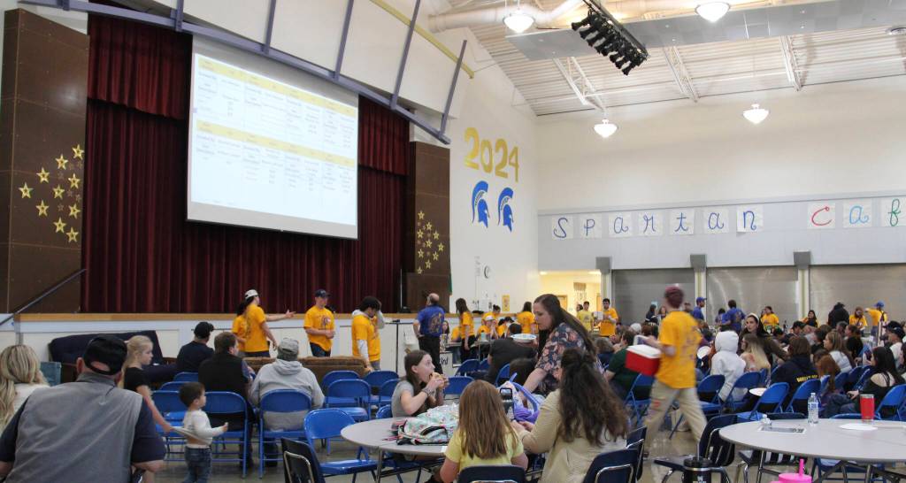 Auctioneer Rod, center of the photo, checks the board as FHS seniors scurry about the crowd …while others enjoy something to eat.