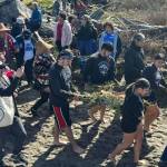 The crowd follows as students make their way to the beach to send off the offering of salmon.