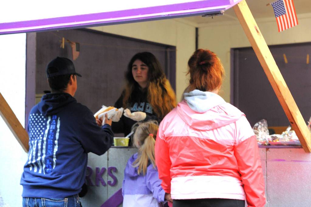 Volunteer Isabella Hayworth passes out hot dogs to one of the many Kids Fishing Day attendees who stopped by the Elks Food Booth for their hot chocolate, hot dogs, and more on Sunday morning.